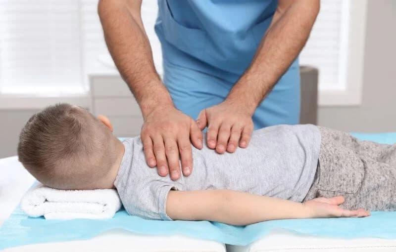 Pediatric chiropractor gently caring for a young child