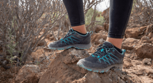 Woman in sneakers standing on a boulder outdoors